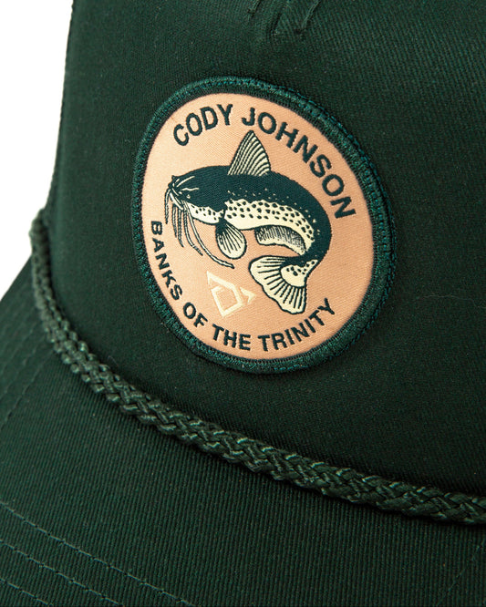 Green cap with a custom round Cody Johnson patch with a catfish and Banks of the Trinity text