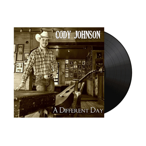 Vinyl record with a cover featuring a man in a cowboy hat and plaid shirt, titled 'A Different Day' by Cody Johnson.