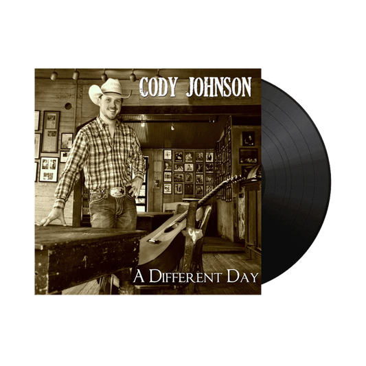 Vinyl record with a cover featuring a man in a cowboy hat and plaid shirt, titled 'A Different Day' by Cody Johnson.
