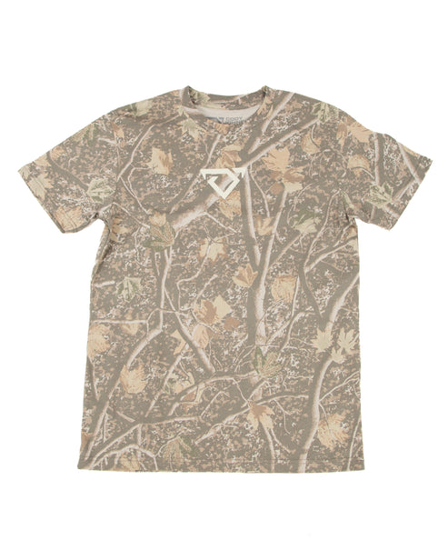A short-sleeve crewneck t-shirt featuring an all-over camouflage pattern of branches and leaves in shades of brown, beige, and gray, with a small cream COJO bull logo on the center chest.