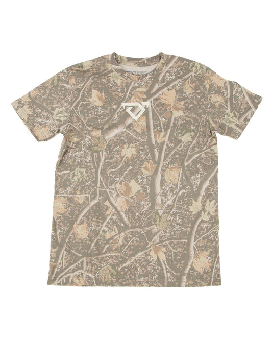 A short-sleeve crewneck t-shirt featuring an all-over camouflage pattern of branches and leaves in shades of brown, beige, and gray, with a small cream COJO bull logo on the center chest.