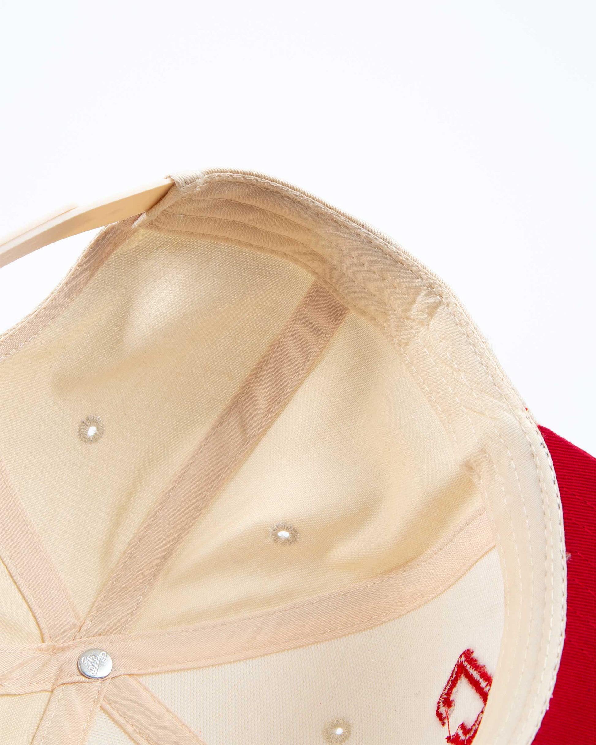 Close-up of a beige cap with red logo on a white background