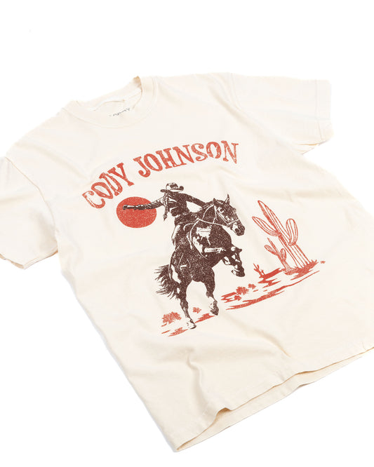 Folded t-shirt with cowboy graphic and 'Cody Johnson' text on a white background